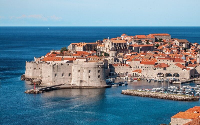 Staré město Dubrovníku s pevnostními hradbami a oranžovými střechami nad modrým Jaderským mořem