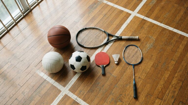 Míče a rakety různých sportů na dřevěné podlaze