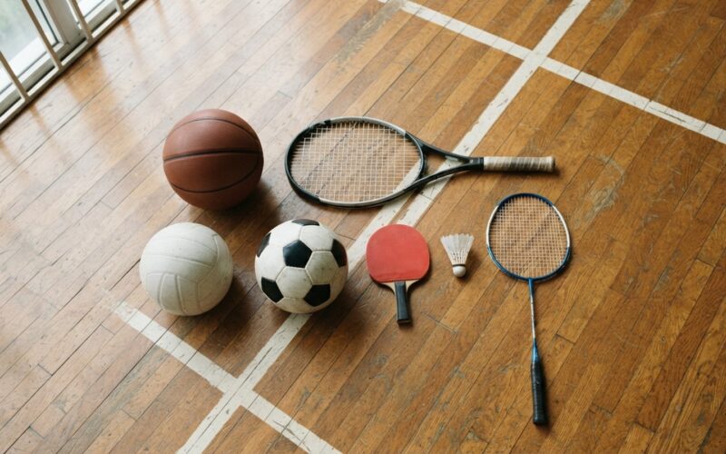 Míče a rakety různých sportů na dřevěné podlaze